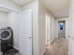 Laundry area with dark tile flooring, white shelving, and a paneled door - 