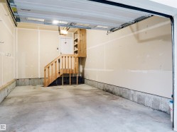 Concrete flooring, wood staircase, built-in shelving, overhead lighting, and an automatic garage door opener - 