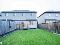 Expansive backyard featuring a manicured lawn, wood fencing, and a built-in wood deck - 