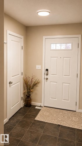 White paneled front door with upper transom windows and smart lock hardware - 5407 14 Avenue Sw, Edmonton, AB 