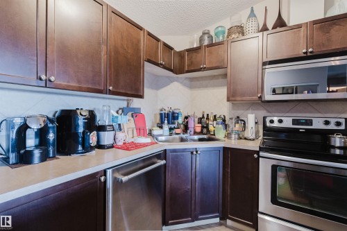 Rich wood-finish cabinetry, stainless steel appliances, durable laminate countertops, and a double basin sink - #7428 7327 South Terwillegar Dr Nw, Edmonton, AB 