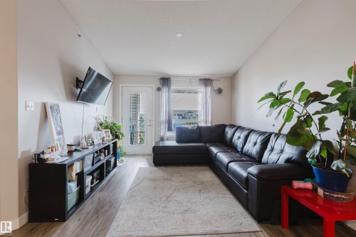 Wood-finish flooring throughout, with a white paneled door to the exterior, and a single window with curtain rods - #7428 7327 South Terwillegar Dr Nw, Edmonton, AB 