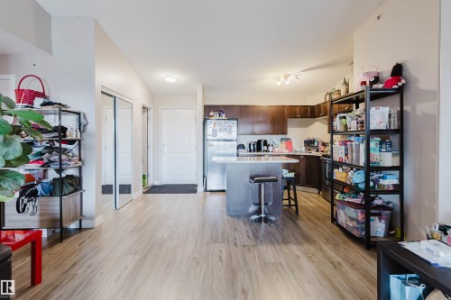 Open-concept living area featuring wood-finish flooring, a kitchen with dark cabinetry, and a central island - #7428 7327 South Terwillegar Dr Nw, Edmonton, AB 