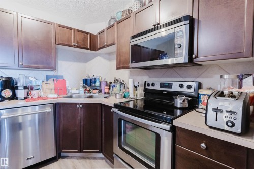 Wood-finish cabinetry, stainless steel appliances, and L-shaped countertop - #7428 7327 South Terwillegar Dr Nw, Edmonton, AB 