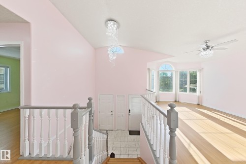 Vaulted ceiling with an ornate chandelier, bay window with arched transom, wood-finish flooring, and a ceiling fan with integrated lighting - 3015 37 Street Nw, Edmonton, AB 