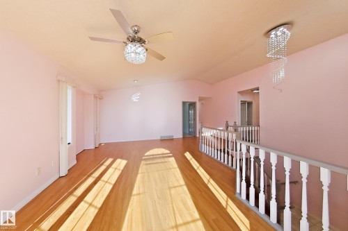 Vaulted ceilings, wood-finish flooring, two decorative chandeliers, a ceiling fan, and white painted railings - 3015 37 Street Nw, Edmonton, AB 
