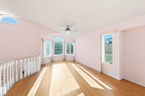 Bay window with arched transom, wood-finish flooring, ceiling fan with decorative light fixture, and an additional arched window - 3015 37 Street Nw, Edmonton, AB 