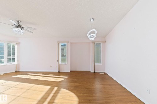 Wood-finish flooring, multiple windows, ceiling-mounted fan, and a contemporary pendant light fixture - 3015 37 Street Nw, Edmonton, AB 