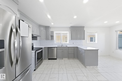 Kitchen featuring white tile flooring, stainless steel appliances, light gray cabinetry, and recessed lighting - 3015 37 Street Nw, Edmonton, AB 