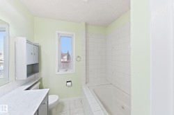Bathroom featuring a built-in bathtub, white wall tiling, and a window with natural light - 