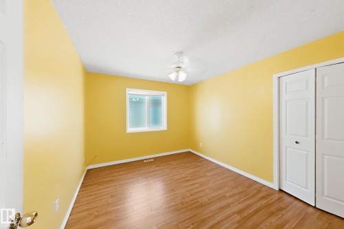 Wood-finish flooring, white bi-fold closet doors, white window frame, and a ceiling light fixture - 3015 37 Street Nw, Edmonton, AB 