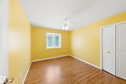 Wood-finish flooring, white bi-fold closet doors, white window frame, and a ceiling light fixture - 