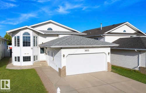 White siding exterior with an attached garage, arched window, and concrete driveway - 3015 37 Street Nw, Edmonton, AB 