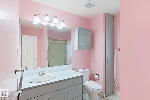 Bathroom featuring a vanity with an integrated sink, a large wall-mounted mirror, overhead lighting, a built-in wall cabinet, and a shower enclosure - 3015 37 Street Nw, Edmonton, AB 