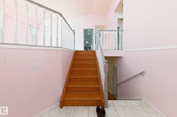 Hardwood staircase with painted balusters, white tile flooring, and vaulted ceiling - 