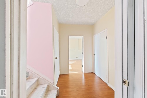 Wood-finish flooring throughout, multiple white doors, and a staircase featuring tiled steps - 3015 37 Street Nw, Edmonton, AB 