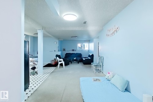 Expansive open living area featuring light blue wall finishes, recessed lighting, and a combination of carpet and tiled flooring - 3015 37 Street Nw, Edmonton, AB 