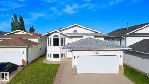 Two-story exterior with white siding, an attached garage, a bay window with multiple panes, and a concrete driveway - 3015 37 Street Nw, Edmonton, AB 