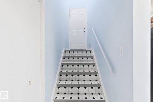 Staircase featuring patterned risers, light blue wall paint, and a handrail - 3015 37 Street Nw, Edmonton, AB 