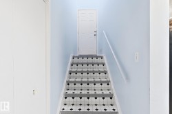 Staircase featuring patterned risers, light blue wall paint, and a handrail - 