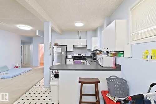 Kitchen with white cabinetry, stainless steel refrigerator, and integrated cooking appliances - 3015 37 Street Nw, Edmonton, AB 