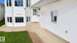 White vinyl siding exterior with a two-story bay window featuring multiple panes and substantial glazing - 