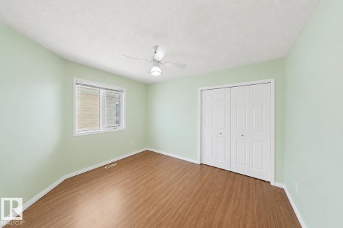 Wood-finish flooring, white window trim, dual-panel bi-fold closet doors, and ceiling-mounted fan with integrated lighting - 3015 37 Street Nw, Edmonton, AB 