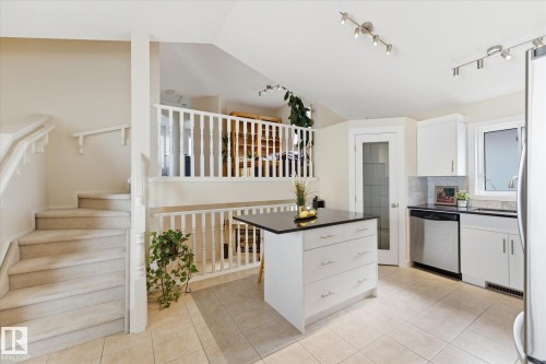Kitchen featuring white cabinetry, stainless steel appliances, a center island with a dark countertop, and tile flooring - 1709 Turvey Bend Bend Nw, Edmonton, AB 