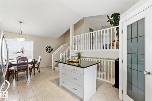 Kitchen island with dark countertop, tiled flooring, built-in staircase, and frosted glass door - 1709 Turvey Bend Bend Nw, Edmonton, AB 