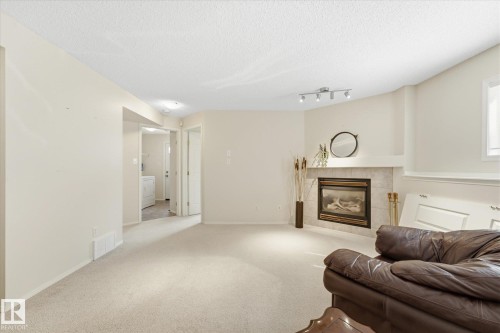 Corner fireplace with a tile surround and mantle, recessed lighting, and soft neutral carpeting - 1709 Turvey Bend Bend Nw, Edmonton, AB 
