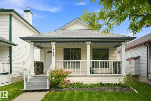 Front porch with white columns, horizontal siding, and a shingled roof - 1709 Turvey Bend Bend Nw, Edmonton, AB 