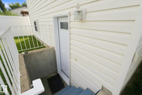 Exterior featuring horizontal siding, a white metal railing, and a windowed entry door with an overhead light fixture - 1709 Turvey Bend Bend Nw, Edmonton, AB 