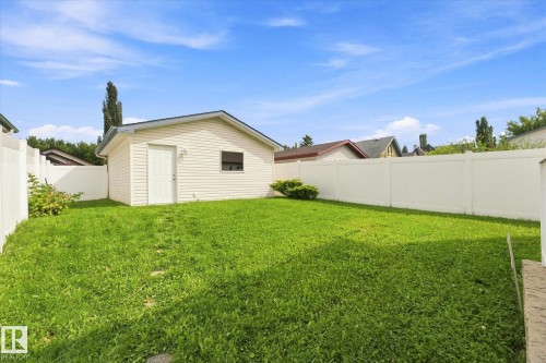Expansive backyard featuring a manicured lawn, white privacy fencing, and a detached structure with siding - 1709 Turvey Bend Bend Nw, Edmonton, AB 