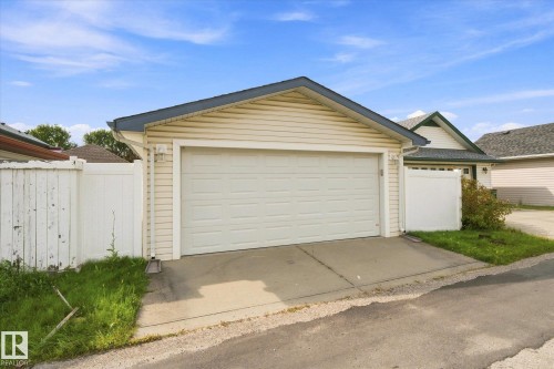 Attached two-car garage with a panel door, vinyl siding, and a dark shingle roof - 1709 Turvey Bend Bend Nw, Edmonton, AB 