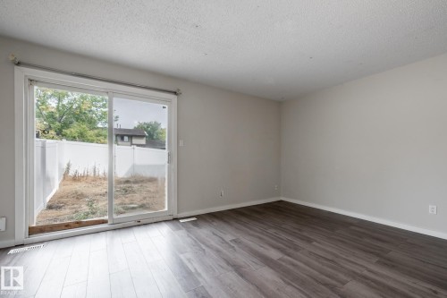 Sliding glass door, wood-finish flooring, light-toned walls, and a white fence - 54 Lakewood Village Nw, Edmonton, AB 