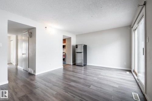 Wood-finish flooring throughout, bright white walls, and a sliding glass door - 54 Lakewood Village Nw, Edmonton, AB 