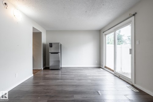 Spacious room featuring wood-finish flooring, light grey walls, and a large sliding glass door - 54 Lakewood Village Nw, Edmonton, AB 