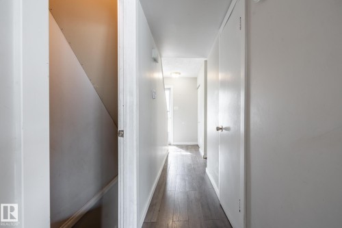 Hallway featuring wood-finish flooring, white walls, and white trim - 54 Lakewood Village Nw, Edmonton, AB 