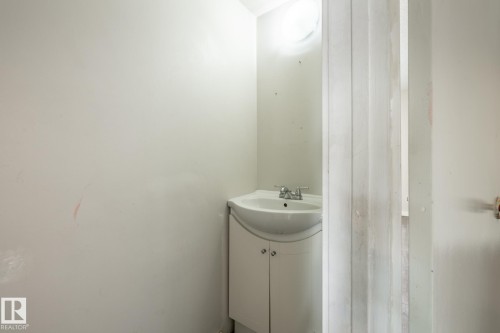Pedestal sink with chrome faucet, integrated vanity cabinet, and wall-mounted light fixture - 54 Lakewood Village Nw, Edmonton, AB 