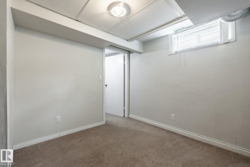 Carpeted flooring with painted walls, a drop ceiling, and a window with blinds - 54 Lakewood Village Nw, Edmonton, AB 