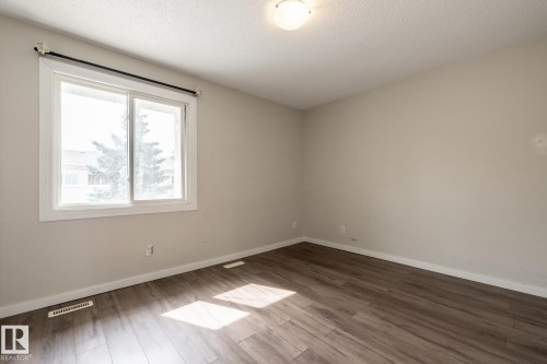 Wood-finish flooring, neutral wall tones, white trim, and a flush mount ceiling light fixture - 54 Lakewood Village Nw, Edmonton, AB 