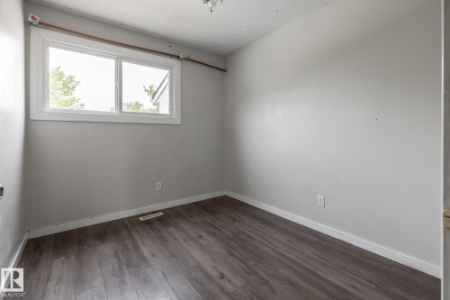 Wood-finish flooring with white trim, light gray walls, and a large window - 54 Lakewood Village Nw, Edmonton, AB 