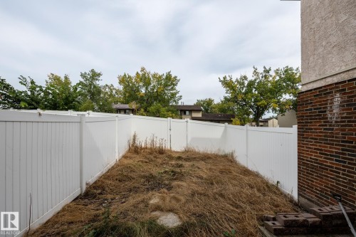 Enclosed rear yard with white panel fencing and a brick and stucco exterior wall - 54 Lakewood Village Nw, Edmonton, AB 