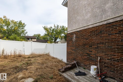White privacy fencing, brick exterior, stucco siding, and wooden deck platform - 54 Lakewood Village Nw, Edmonton, AB 