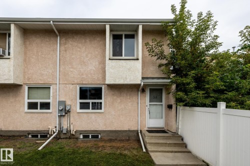 Concrete steps leading to the front entry, white privacy fence, mature trees, and a stucco exterior - 54 Lakewood Village Nw, Edmonton, AB 