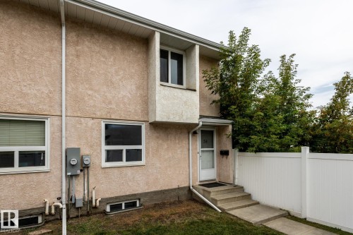Stucco exterior, white vinyl fencing, concrete steps, white trim windows, and a storm door - 54 Lakewood Village Nw, Edmonton, AB 