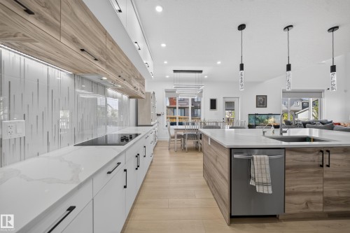 Quartz countertops, wood-finish cabinetry, stainless steel dishwasher, integrated cooktop, and wood-finish flooring - 17128 2 Street Nw, Edmonton, AB 