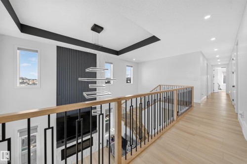 Hallway overlooking the open-to-above living room with huge windows for an abundance of natural light. - 17128 2 Street Nw, Edmonton, AB 