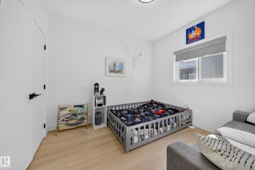 Light wood-finish flooring, white walls, and a window with a roller shade - 17128 2 Street Nw, Edmonton, AB 