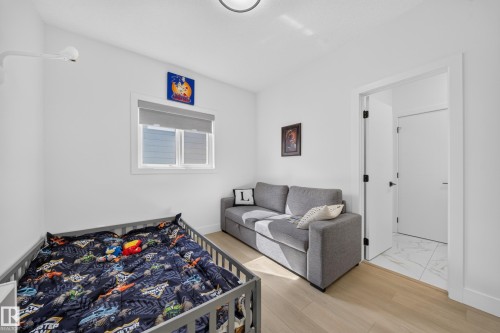 Light wood-finish flooring, white walls, and a window with a roller shade - 17128 2 Street Nw, Edmonton, AB 